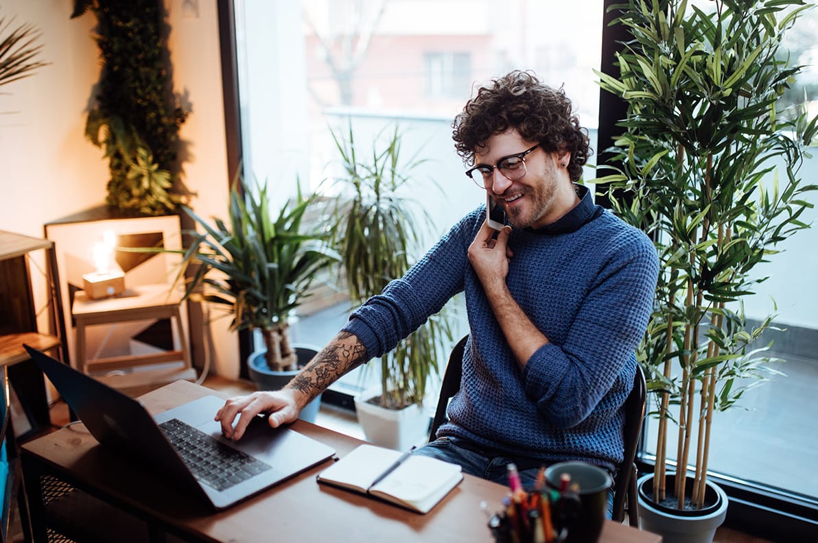 man on a desk using a phone and computer